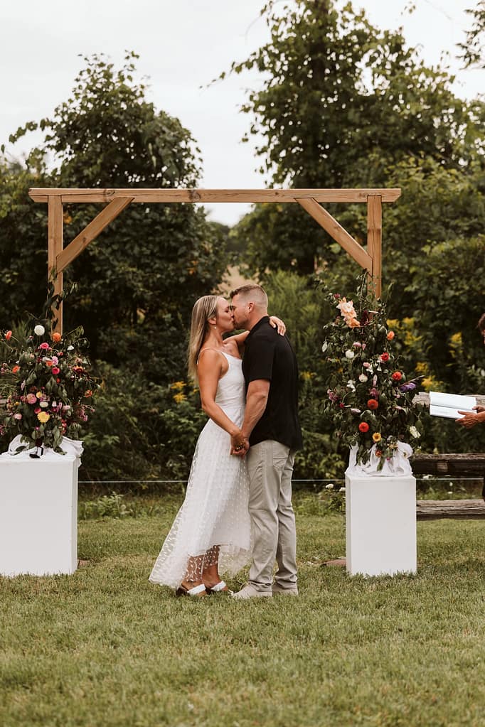 blog post our wedding story bride and groom kiss at floral arch